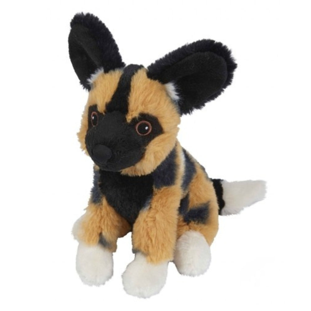 A small African wild dog plush toy with black and tan fur, white paws, and large upright ears, photographed on a plain white background.